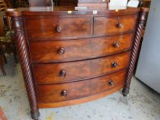 An antique flame mahogany bow fronted chest of drawers with barley-twist supports, two short above