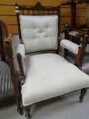An early twentieth century wooden framed cushion back seated armchair