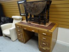 A vintage light oak kneehole desk with four banks of drawers to either side of a central drawer