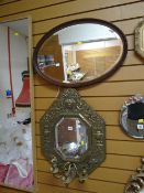 An antique decorative brass framed bevelled wall mirror with three-branch candelabra sconce together