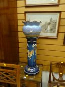 A pottery planter on a floral painted pottery pedestal