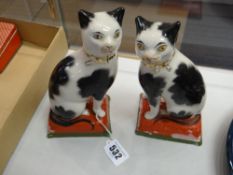 A pair of seated Staffordshire porcelain black & white cats
