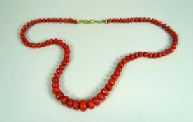 A NECKLACE OF FACETED GRADUATED CORAL BEADS with believed 18ct yellow gold clasp, 54cms long