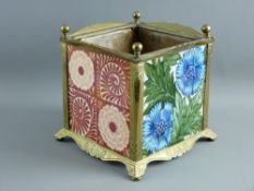 FOUR EARLY WILLIAM DE MORGAN POTTERY TILES housed in a square brass planter frame with ball finials,