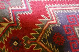 A BALOCHI WOVEN WOOL RUG with traditional stylized pattern on a predominantly green ground, 146 x 91