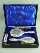 A CASED FOUR PIECE SET OF SILVER BACKED DRESSING TABLE WARE, all scroll and floral decorated -