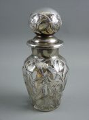A SILVER OVERLAY SMELLING SALTS BOTTLE WITH STOPPER having a pierced foliate design overlay on