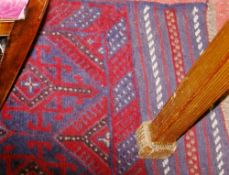 A MESHWANI RUNNER, a mixed red and blue ground tribal rug having a repeated pattern and wide