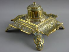 A DECORATIVE SQUARE BRASS INKSTAND with centre bowl and having white ceramic container (cracked)