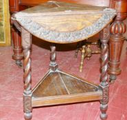 A CIRCA 1930 CARVED OAK CRICKET TABLE in triangular form with triple flaps opening to form a