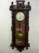 A WALNUT CASED VIENNA STYLE WALL CLOCK, twin weight pendulum driven movement striking on a coiled
