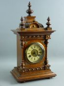 A CIRCA 1900 GERMAN OAK CASED MANTEL CLOCK, architecturally styled with finial caps and decorative
