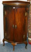 A GEORGIAN MAHOGANY BOW FRONT FLOORSTANDING CORNER CABINET, the railback top over twin doors with