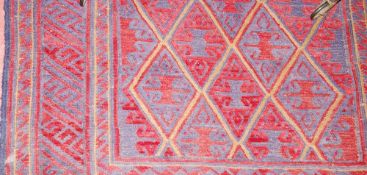 A TRIBAL KAZAK RUG, deep red ground woollen woven rug with central repeated diamond pattern and