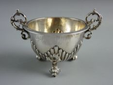 A CIRCULAR SILVER TWIN HANDLED POT on three leaf and dolphin mask supports, maker's LOT WITHDRAWN