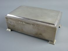 AN OBLONG SILVER CIGARETTE BOX on corner bracket feet and with engine turned lid, two compartment