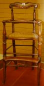 A CHILD'S HIGH DINING CHAIR with cane seat, turned arms, safety rail and foot step