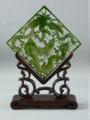 A CARVED GREEN JADE TABLE SCREEN on wooden stand, the pierced panel depicting a dragon and phoenix