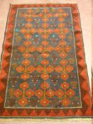A BALOCHI RUG, crimson red and blue ground with central repeating tree and floral pattern with zig