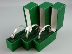 THREE SILVER BANGLES one with padlocked fastener, the two others with safety chains, hallmarked