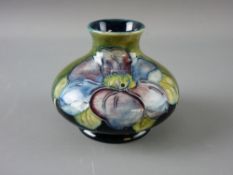 A SMALL MOORCROFT 'CLEMATIS' SQUAT VASE decorated on a tonal green ground, original paper label to