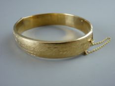 A NINE CARAT GOLD HALF BRIGHT CUT HOLLOW BANGLE, 21.5 grms gross