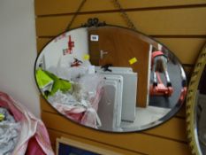 A vintage bevelled oval wall mirror with metallic frame