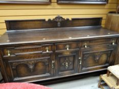An early twentieth century stained oak English sideboard with carved detail & brass fittings