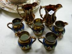 Set of five blue banded decorated copper lustre jugs and two other copper lustre jugs