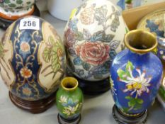 Two decorative porcelain eggs on stands and two cloisonne vases on hardwood stands