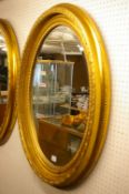 A LARGE REPRODUCTION WALL MIRROR in classically styled oval gilt frame with bevelled edge glass,