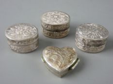 FOUR SMALL FLORAL DECORATED SILVER PILL BOXES including a heart shaped example with hinged lid