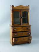 AN APPRENTICE PIECE MAHOGANY BOOKCASE CHEST having two upper glazed doors on a base of three long