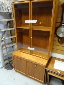A G-plan teak lounge unit comprising cupboard base & glazed bookcase top