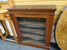 An antique mahogany single glazed door music cabinet