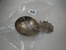 A silver tea strainer with lion head heraldic handle