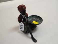 A painted metallic figure of a seated Arabian pedlar