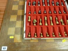 Chess board with a box set of metallic chess pieces