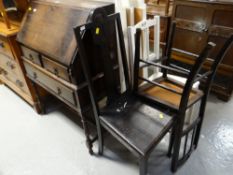 A vintage oak slope fronted bureau on raised legs together with three various wooden chairs