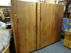 A set of three Brynmawr Furniture co-operative oak wardrobes, each with a single door and with