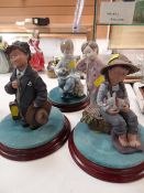 A Nao figure of a pyjama wearing boy holding Teddy bear together with another of boy seated with