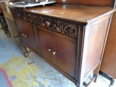 A vintage oak railback sideboard with decorative carving to two drawers above a two cupboard