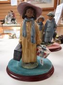 A Lladro model of a girl in trench coat with luggage