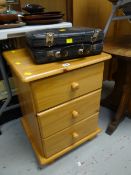 A narrow modern pine effect three-drawer chest