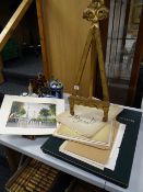 A gilt decorated wooden table easel & a parcel of unframed watercolours & prints together with a