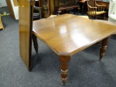 A winding extending Edwardian oak dining table with two leaves