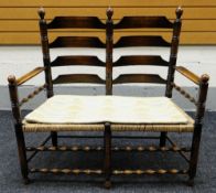 A TWO-SEATER OAK FRAMED RUSH SEATED LADDER BACK SETTEE Provenance: Estate of Helen Zienkiewicz