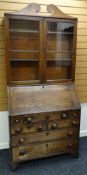 AN EARLY NINETEENTH CENTURY OAK BUREAU BOOKCASE having a two door glazed top with sloped front