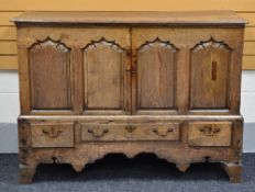 AN EARLY NINETEENTH CENTURY OAK BLANKET CHEST converted to shelved cupboard and having a three