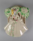 A CLARICE CLIFF WALL POCKET featuring a lady in floral dress & bonnet standing beside a line of